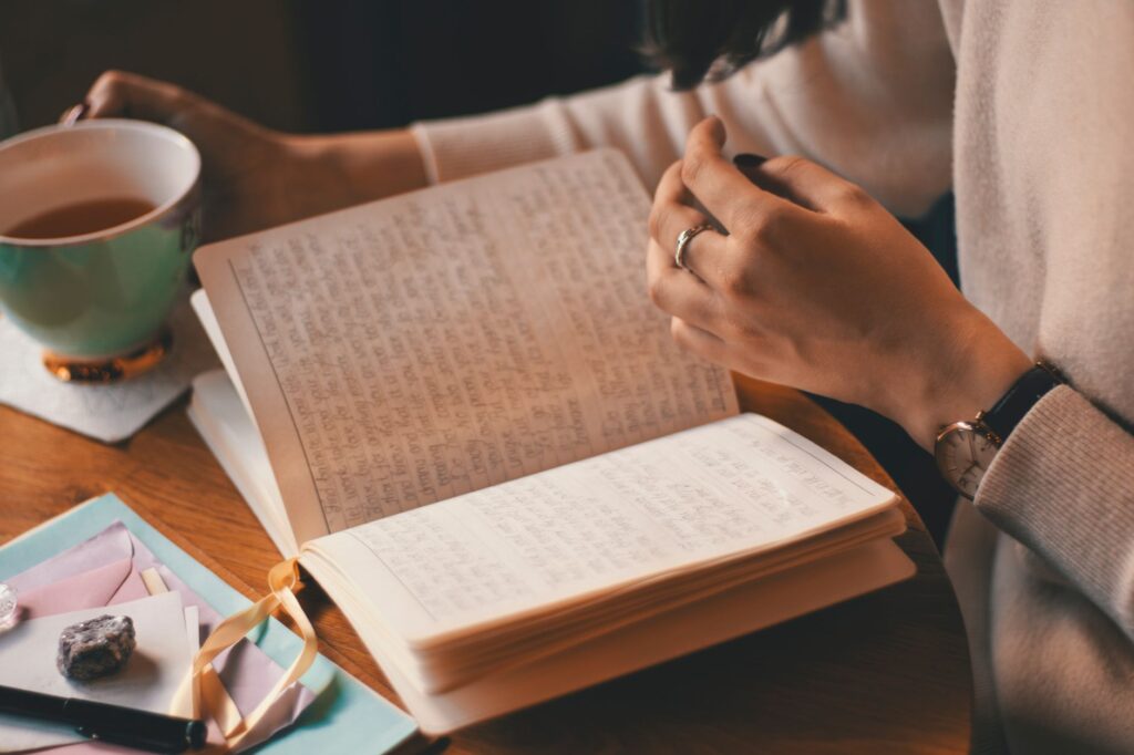 Une main annote un carnet posé sur une table en bois